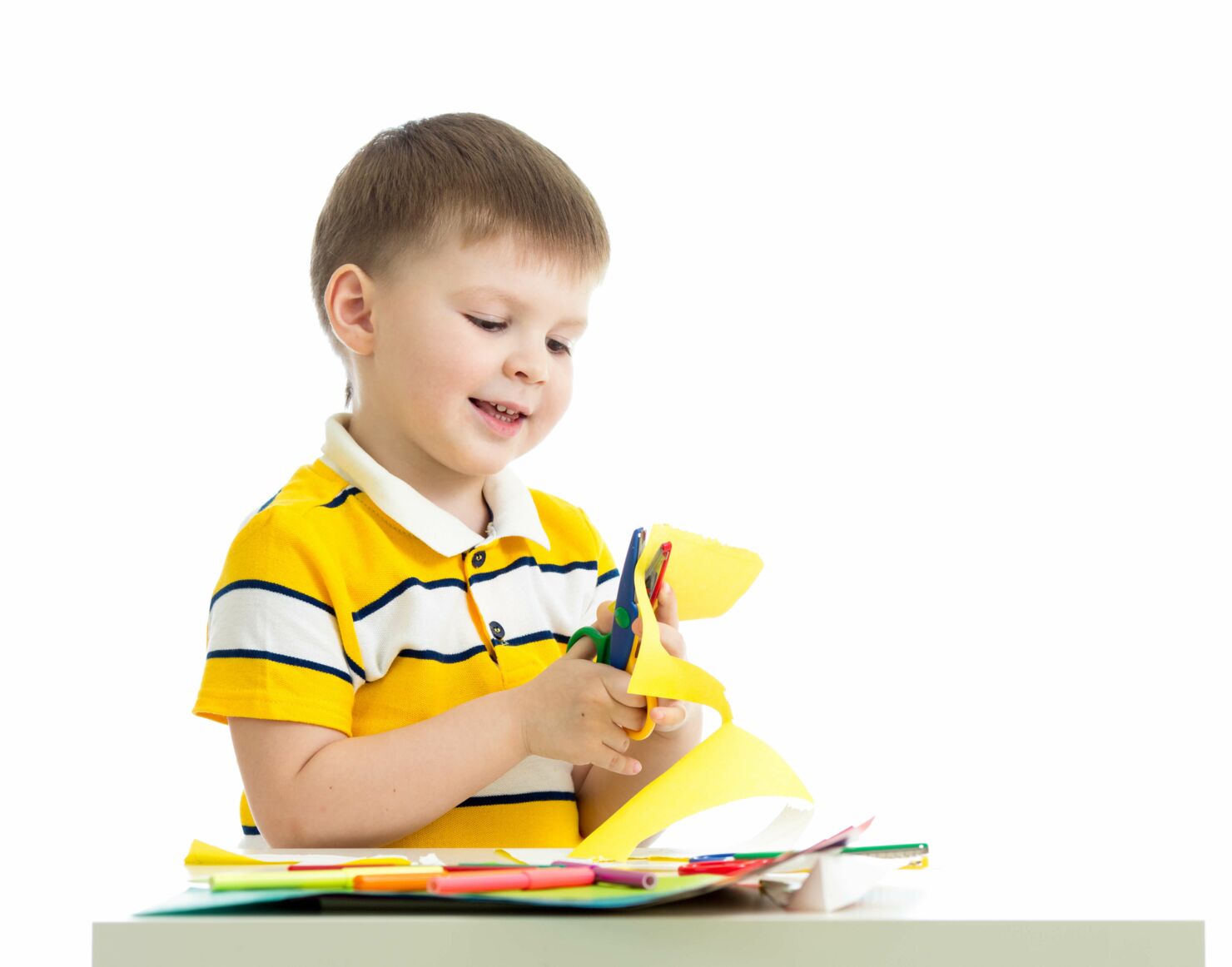 Ein Kind schneidet Tonpapier und lacht