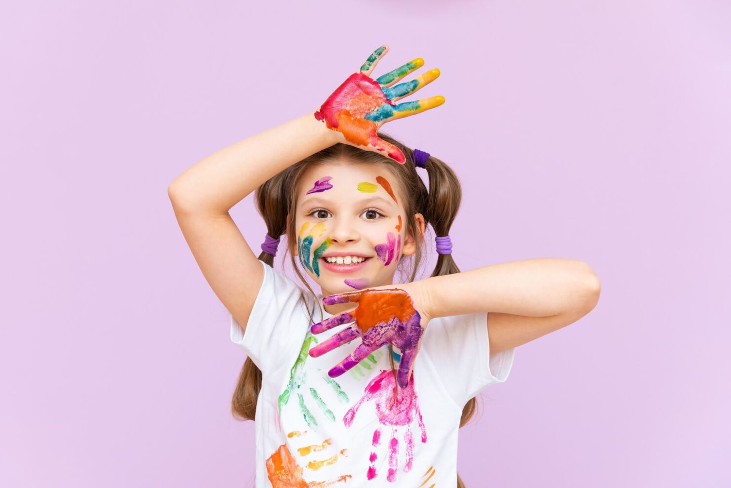Ein Mädchen hat mehrere Handabdrücke aus Farben an ihrem Gesicht und T-Shirt