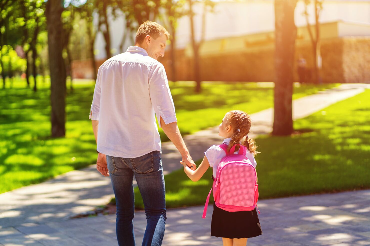 Ein kleines Mädchen läuft mit ihrem Vater im Park, sie schauen sich strahlend an